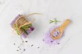 Lavender soap, violet salt on wooden spoon and fresh flowers on white marble background. Bath body care or spa wellness concept