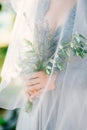 Lavender Wedding bouquet in hands of the bride under veil in pal