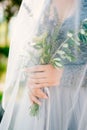 Lavender Wedding bouquet in hands of the bride under veil in pal