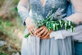 Lavender Wedding bouquet in hands of the bride in white-blue dre