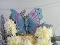 Lavender wreath with white carnations and a blue and purple mesh butterfly with gemstones and a sandstone background. Spring home