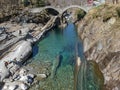 Tourists visiting the famous roman bridge of Lavertezzo on Verzasca valley on the italian part of Switzerland Royalty Free Stock Photo