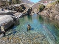 Tourists visiting the famous roman bridge of Lavertezzo on Verzasca valley on the italian part of Switzerland Royalty Free Stock Photo