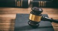 Law or auction gavel on a book, wooden office desk background. Closeup front view