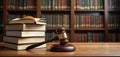 Law books, judge gavel displayed on wooden table in courtroom setting. Law books stack on table. Many books visible behind books