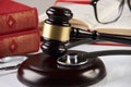 Law books with wooden judges gavel and medical stethoscope