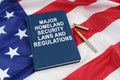 On the US flag lies a pen and a book with the inscription - MAJOR HOMELAND SECURITY LAWS AND REGULATIONS