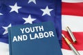 On the US flag lies a pen and a book with the inscription - YOUTH AND LABOR
