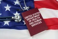 On the US flag lies a stethoscope and a book with the inscription -United States Department of Health and Human Services Royalty Free Stock Photo