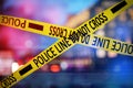 Yellow law enforcement tape isolating crime scene. Blurred view of city, toned in red and blue police car lights Royalty Free Stock Photo