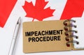 Against the background of the flag of Canada lies a notebook with the inscription - IMPEACHMENT PROCEDURE