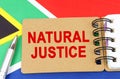 Against the background of the flag of South Africa lies a notebook with the inscription - NATURAL JUSTICE Royalty Free Stock Photo