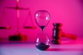 Law and justice theme, Hourglass, scales and wooden judge gavel in pink neon close-up