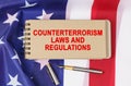 Against the background of the flag of the USA lies a notebook with the inscription - COUNTERTERRORISM LAWS