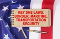 Against the background of the flag of the USA lies a notebook with the inscription - KEY DHS LAWS