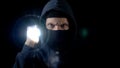 Lawbreaker in balaclava mask flashing torch, searching for important information Royalty Free Stock Photo