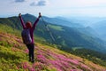 The lawn with the bushes of rhododendron flowers. The girl with back sack. The landscape with cloudy sky, high mountains.