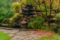 Lawn among decorative bushes with a path and artificial rock with waterfall Royalty Free Stock Photo