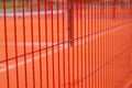 Lawn field for playing basketball behind the orange fence mesh. Metal mesh wire with tennis court. Royalty Free Stock Photo