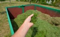 On the lawn is a green tin container for grass clippings from gardens and parks. a man checks the quality and quantity of grass by Royalty Free Stock Photo