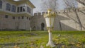 Lawn with lanterns at palace. Action. Green garden at stone walls of small palace. Royal style garden lights on lawn on