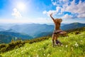 On the lawn in mountains landscapes the hipster girl in dress, stockings and straw hat stays watching the sky with clouds. Royalty Free Stock Photo