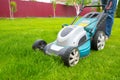 A lawn mover is cutting green grass, the gardener is working with a lawn mower, a close-up, the yard of a private house Royalty Free Stock Photo