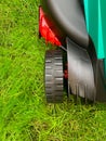 Lawn mower cutting green grass in the backyard. Gardening background.Grass close-up and wheel of a lawn mowing machine, yard care Royalty Free Stock Photo