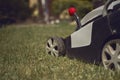 Lawn mower cutting green grass on backyard. Gardening care equipment. Sunny day, close up Royalty Free Stock Photo