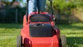 Lawn-mower cutting green grass outdoor in garden. Man mows lawn in the backyard with electric lawn mower. Slow motion