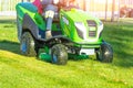 Lawn mower with driver mowing the grass on a green meadow. Royalty Free Stock Photo