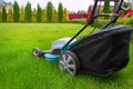 A lawn mower mowing green grass in the house backyard. A close-up of an electric lawn mower