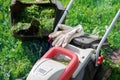 Lawn mower with protective gloves and a grass container full of trimmed grass in the garden Royalty Free Stock Photo