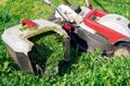 Lawn mower with protective gloves and a grass container full of trimmed grass in the garden Royalty Free Stock Photo