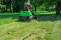 Lawn mower rides on the lawn and mows the grass. Mowing the lawn in the park Royalty Free Stock Photo