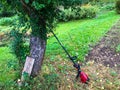 A lawn mower stands near a tree. a mowing machine stands near the apple tree, waiting for the gardener. harvesting yellowed autumn Royalty Free Stock Photo