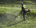 Lawn mower worker cutting grass in green field