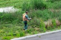 Lawn mower worker cutting grass in green field.Worker mowing tall grass with petrol lawn trimmer in city park or backyard. Royalty Free Stock Photo