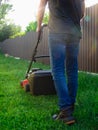 Lawn mowing. A man mows green grass with a lawn mower at sunset. Caucasian Gardener working with lawnmower and cutting grass Royalty Free Stock Photo