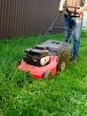 Lawn mowing. A man mows green grass with a lawn mower at sunset. Caucasian Gardener working with lawnmower and cutting grass Royalty Free Stock Photo