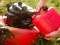Lawn mowing. A man fills up a lawn mower with gasoline. Refilling the fuel tank in a petrol lawn mower Royalty Free Stock Photo