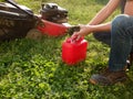 Lawn mowing. A man fills up a lawn mower with gasoline. Refilling the fuel tank in a petrol lawn mower Royalty Free Stock Photo