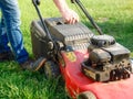 Lawn mowing. A man mows green grass with a lawn mower at sunset. Caucasian Gardener working with lawnmower and cutting grass Royalty Free Stock Photo