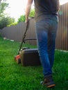 Lawn mowing. A man mows green grass with a lawn mower at sunset. Caucasian Gardener working with lawnmower and cutting grass Royalty Free Stock Photo