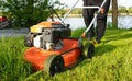 Lawn mowing. Person mowing the grass with orange lawnmower. Mowing in the summer on sunny day. Royalty Free Stock Photo