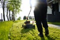 Lawn mowing. Person mowing the grass with orange lawnmower. Mowing in the summer on sunny day. Royalty Free Stock Photo