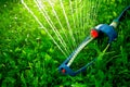 Lawn sprinkler spaying water over green grass. Royalty Free Stock Photo