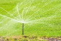 Lawn sprinkler spaying water over green grass, irrigation system. Royalty Free Stock Photo