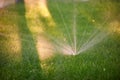 Lawn sprinkler spaying water over green grass. Morning time Royalty Free Stock Photo