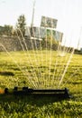 Lawn sprinkler spraying water over green grass. Modern device of irrigation garden grass. Irrigation system - technique